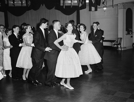 1950s Vintage Photo: A group of teenagers in 1950s dresses & suits for boys doing their own Bunny Hop.