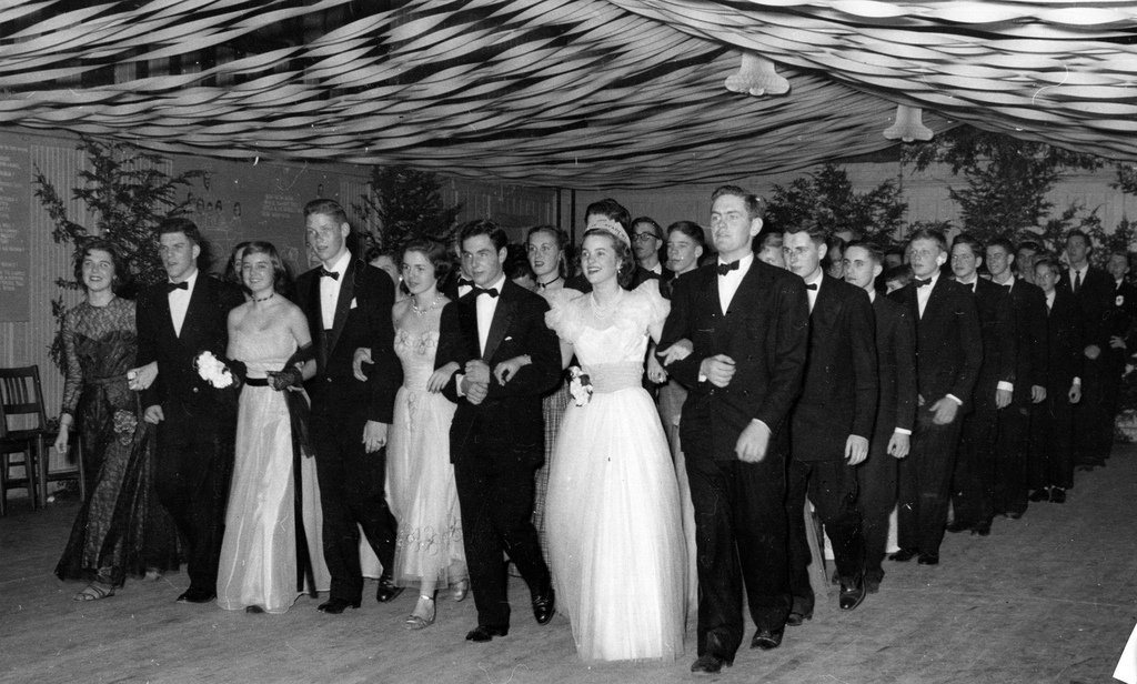 1949 Prom or Formal Dance. 1940s vintage image featuring a group of young men and women in 1940s evening gowns and tuxes lined up at the prom. 