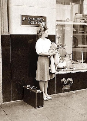 1942 vintage woman on the street with a suitcase in 1940s fashion. 