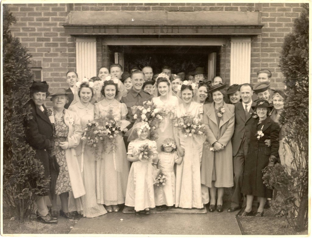 1940s vintage photo of a 1940s WW2 War Bride Wedding. The image features the 1940s bride and her groom and all the wedding guests and bridesmaids. 