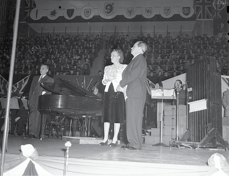 1940s vintage photo of American radio stars Fibber McGee and Molly perform during a Victory Loans Rally in 1945.