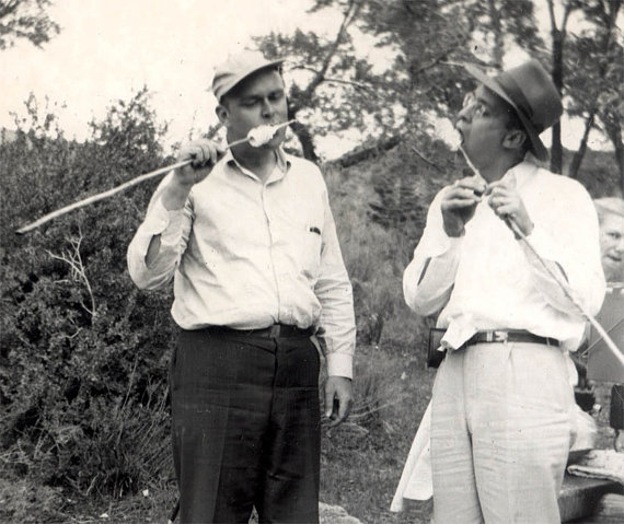 1940s vintage photo of men eating roasted marshmallows while camping. 