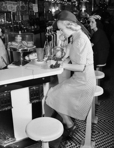 1940s woman at a soda counter in 1940s hait and 1940s dress