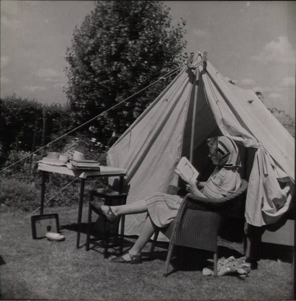 1940s vintage photo of a woman reading a book while camping