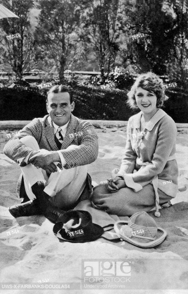 Vintage Photo of Douglas Fairbanks and Mary PIckford sitting on a beach.