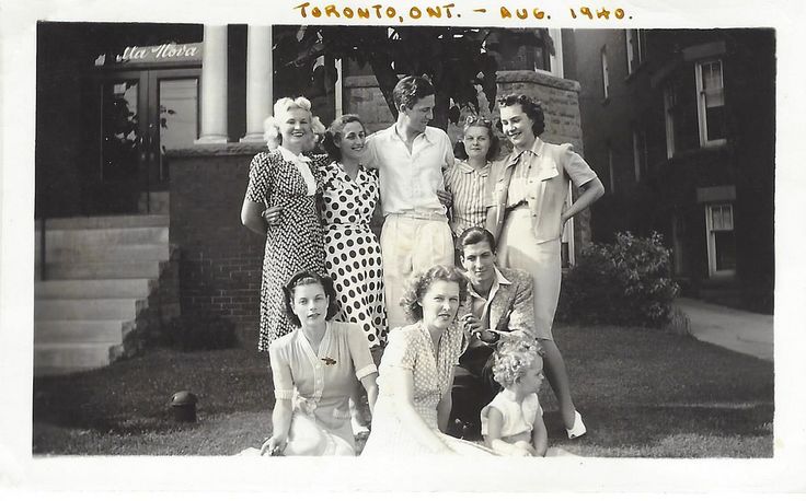 1940s vintage photo of a group of men and women in 1940s fashions posing in front of the house in Toronto, Canada. 