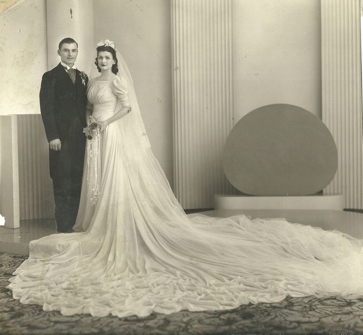 1930's vintage wedding photo featuring a bride in an elegant long train 1930s wedding gown with veil. 