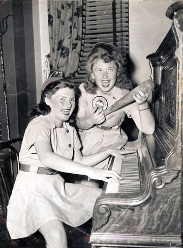 Vintage 1940s Image of women from the All American Girls Baseball league playing their "team song" around a piano.