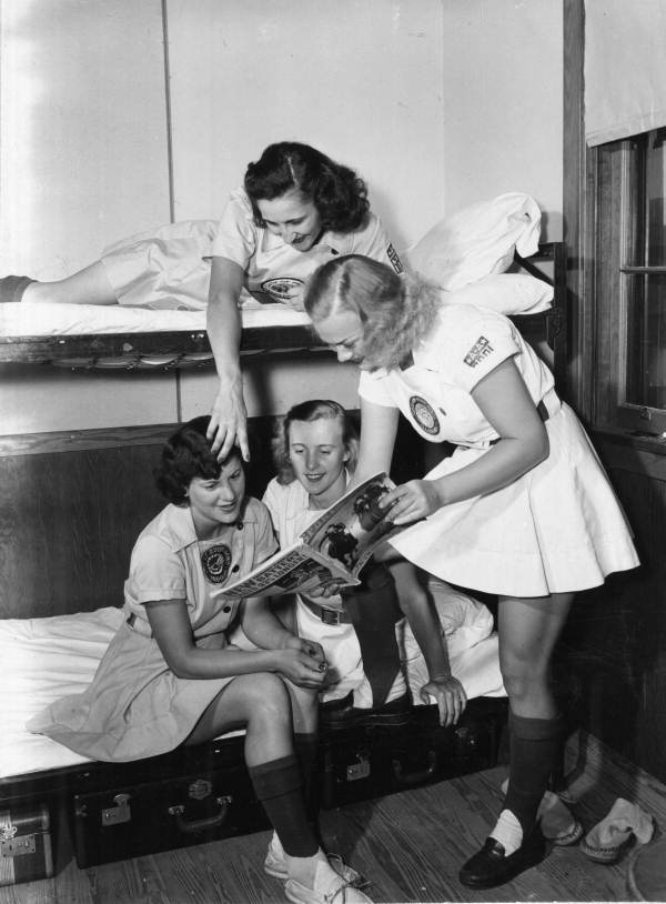 Vintage Photo of all american girls profesionall baseball league players looking at a magazine in their uniforms.