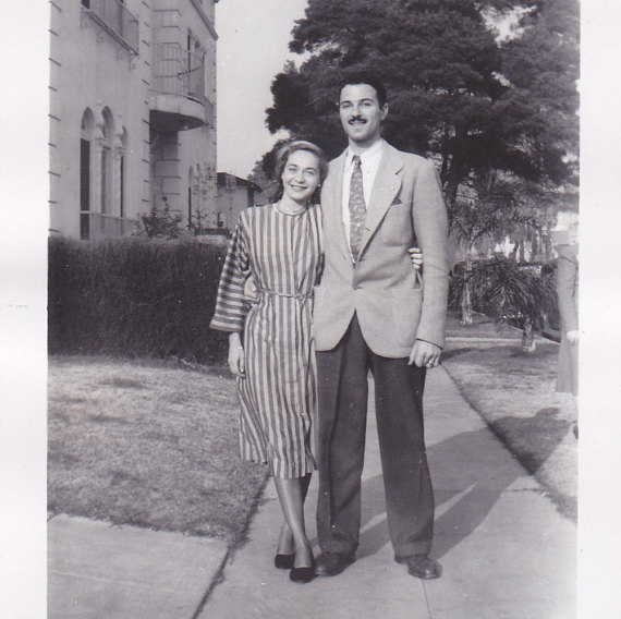 1940s vintage image of a couple posing together on a sidewalk in stylish 1940s fashioins.