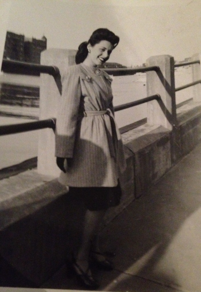 1940s vintage photo of a women with 1940s hairstyle and a 1940s coat posing for a photo. 