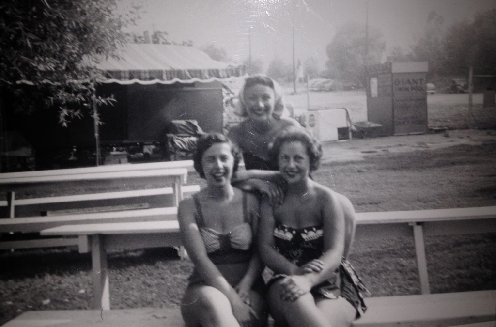 1950s vintage photo of three women in 1950s swimsuits / bathing suits posing for a photo together in 1954.