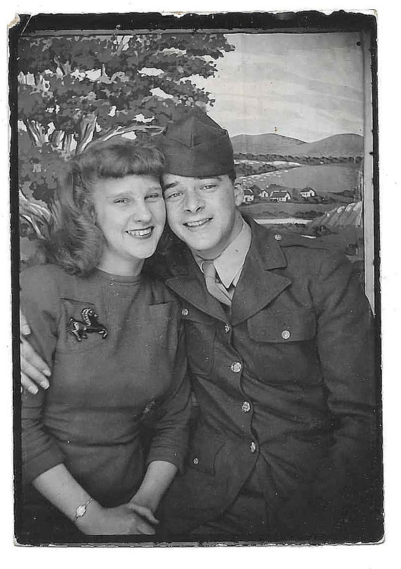 1940s image of soldier and woman  with a horse broach posing in a photo booth. 