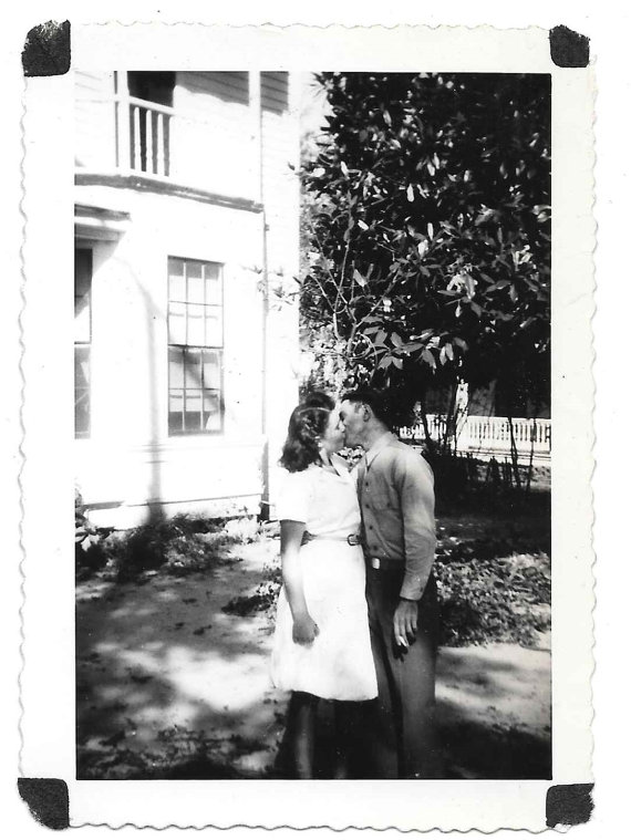 1940s Vintage Photo of a woman in a 1940s dressing kissing a man in uniform during WW2. 