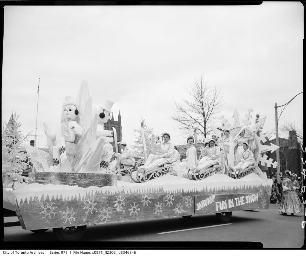 1950s vintage photo of a float in the Toronto Santa Claus parade in 1956. The float features ladies on sleds with snowman and the queen or princess of the parade. 