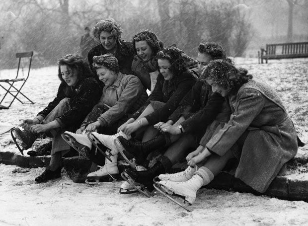 1947 women putting on ice skates. 1940s vintage image of women with 1940s hairstyles