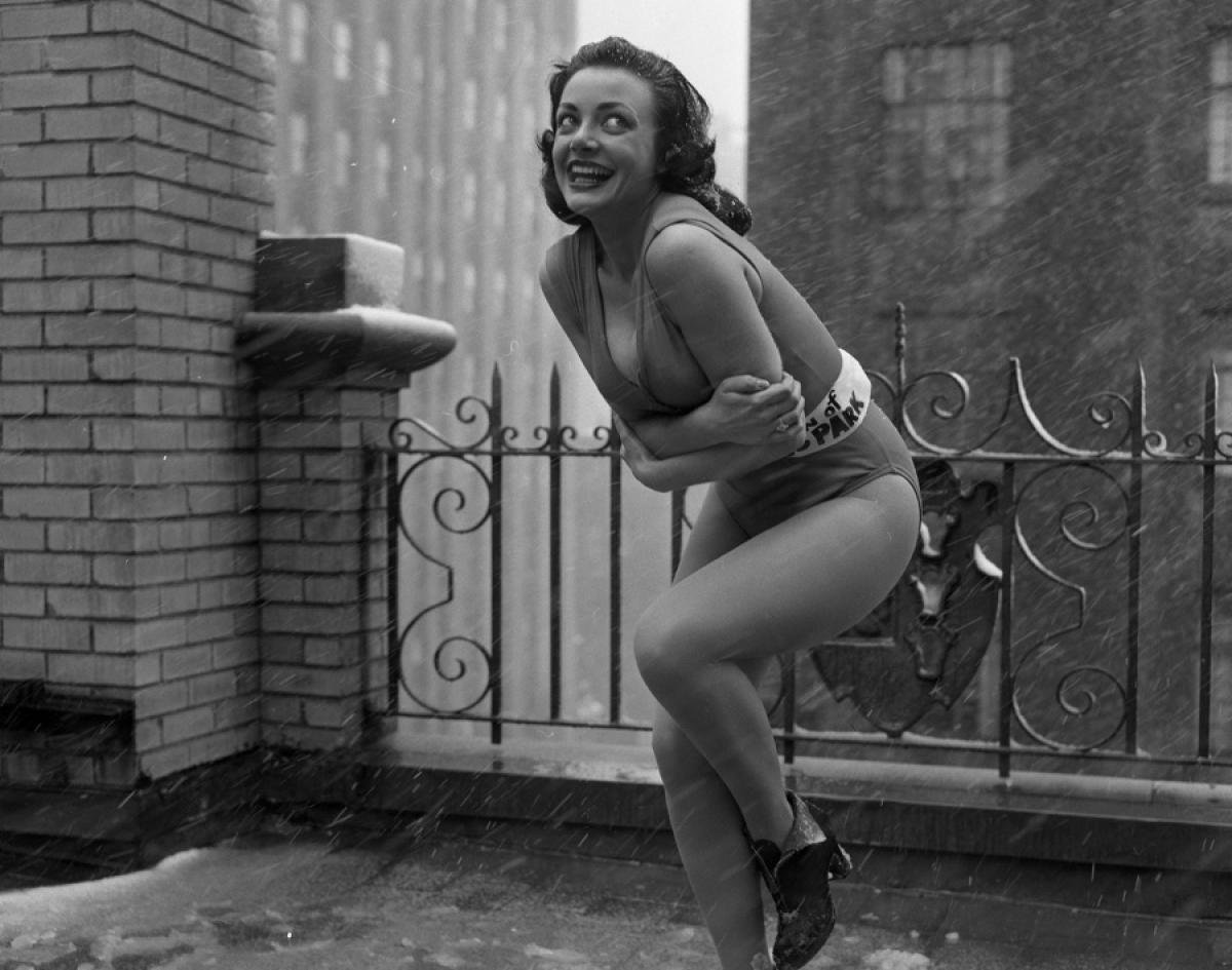 1957 vintage photo of a beauty queen in her swimsuit posing for a picture in New York City during a snowstorm. 