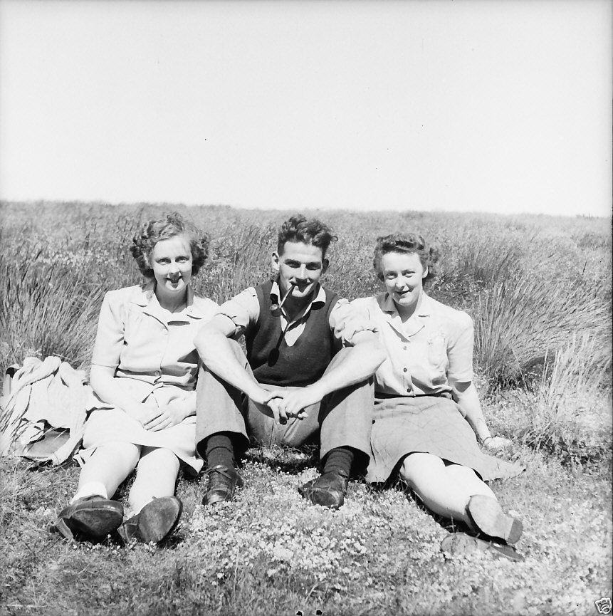 1940s vintage image of 2 women and one man. Women have lovely 1940s hairstyles and pretty 1940s fashions.