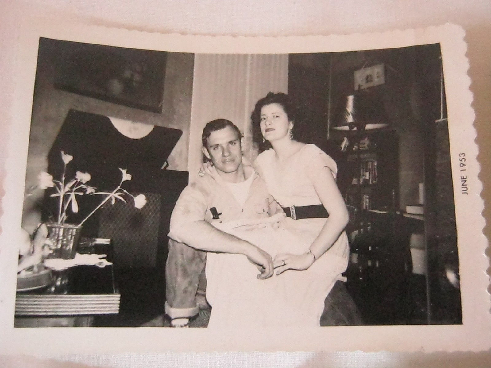 1950s Photo of a couple posing together in their living room featuring a record player in the background. Super 1950s fashions. 