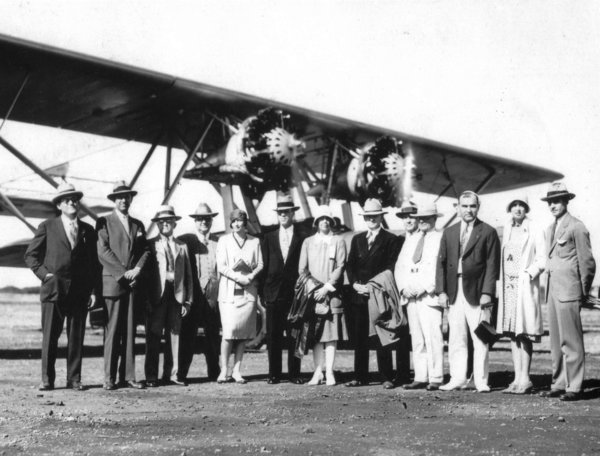 Late 1920s early 1930 fashions on display with people posing with Hawaiian Airlines airplane