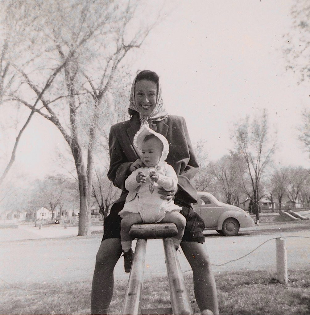 1950s vintage image of mother and child. Mother is wearing a scarf over her hair. 