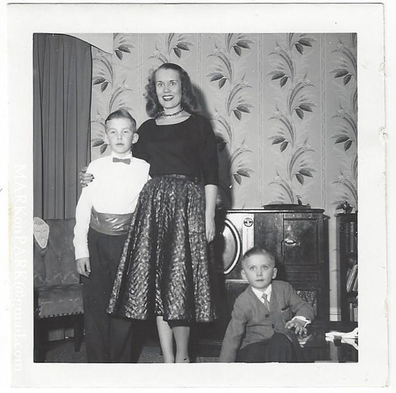 1950s vintage image of mother and children. Mother is wearing a 1950s skirt and pretty 1950s blouse. Boys are dressed up. 