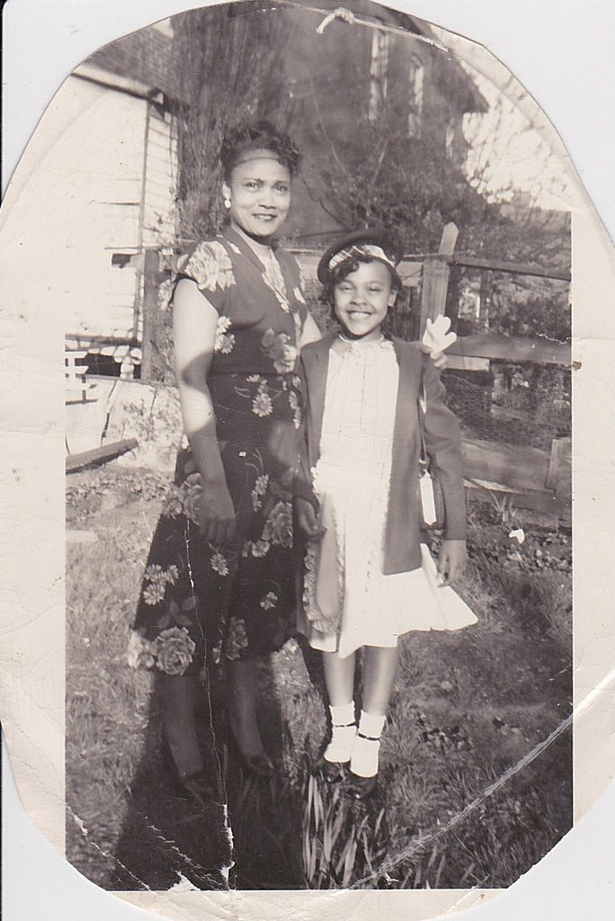 1940s vintage image of a beautiful Black mother and daughter in stylish 1940s fashions posing together.