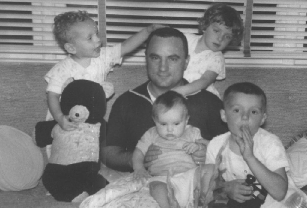 1950s vintage image of father with children on a couch in a livingroom