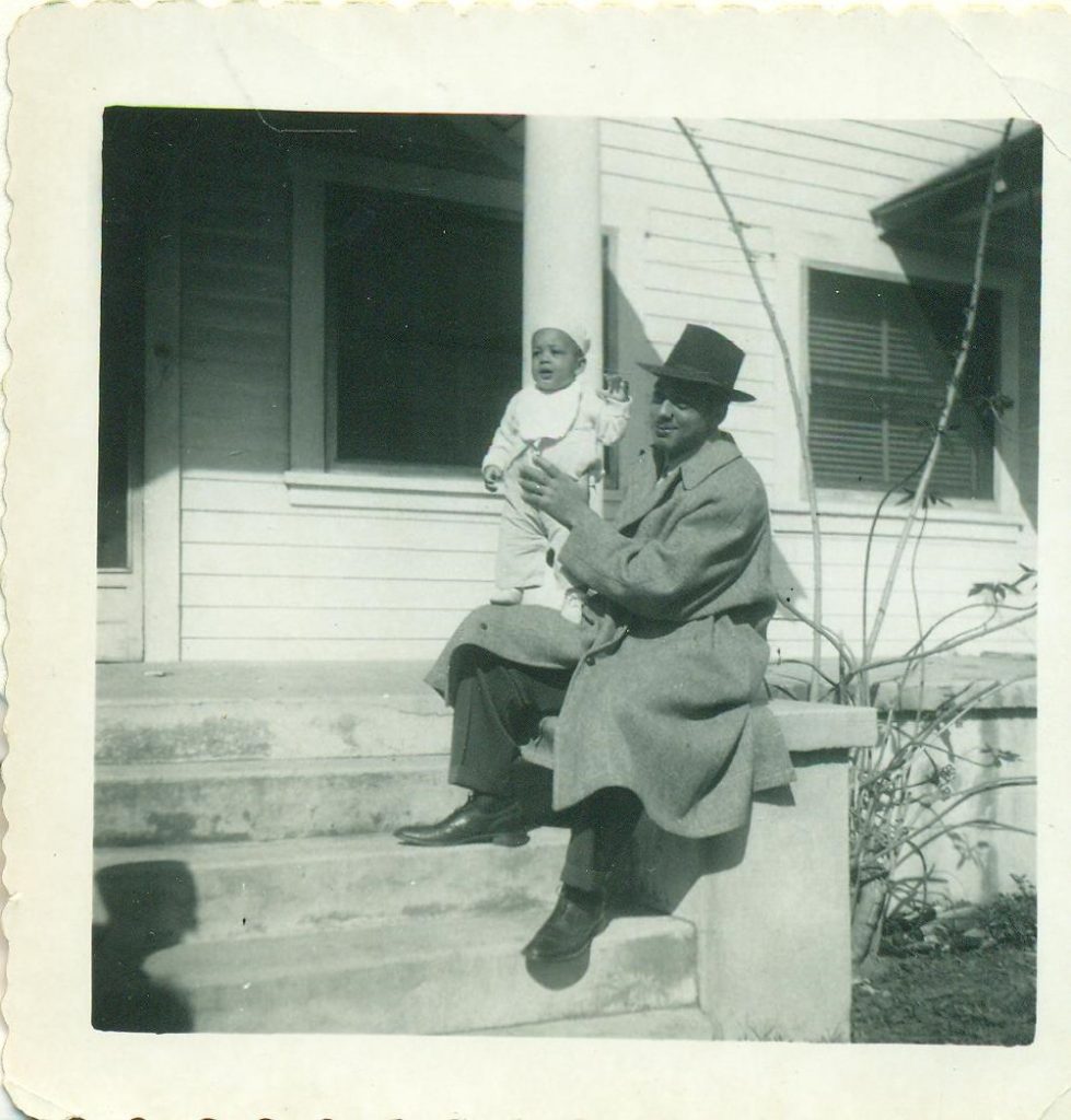 1940s vintage photo of father with baby posing on the front steps. 