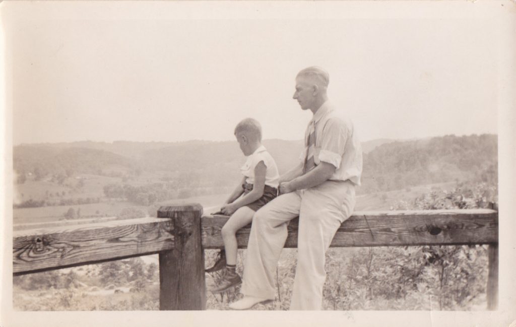 1940s vintage photo of father with son posing on a fence