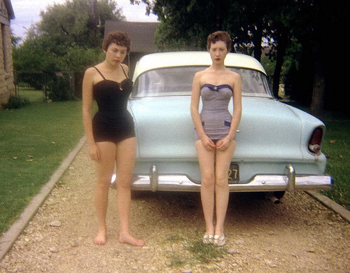 1950s vintage photo of 2 young women in 1950s swimsuits posing with a 1950s car in this colour photo. Great 1950s Fashions!