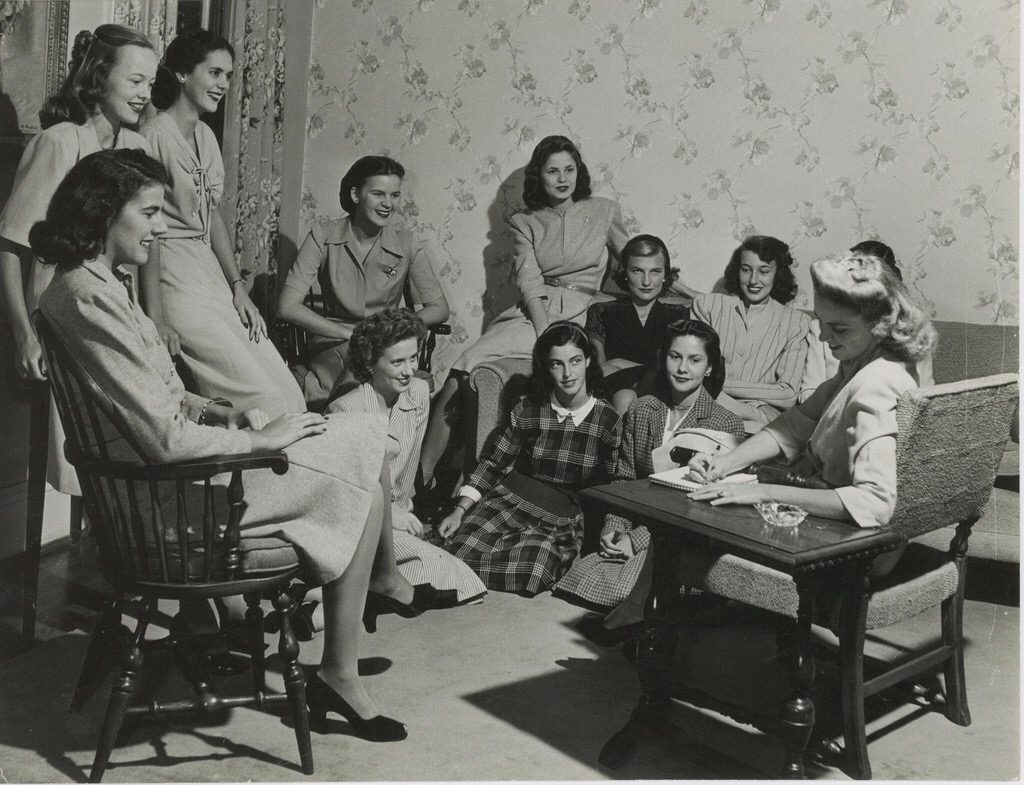 1940s vintage image of a group of young women in their dorm room at a club meeting. Super 1940s fashions and 1940s hairstyles. 