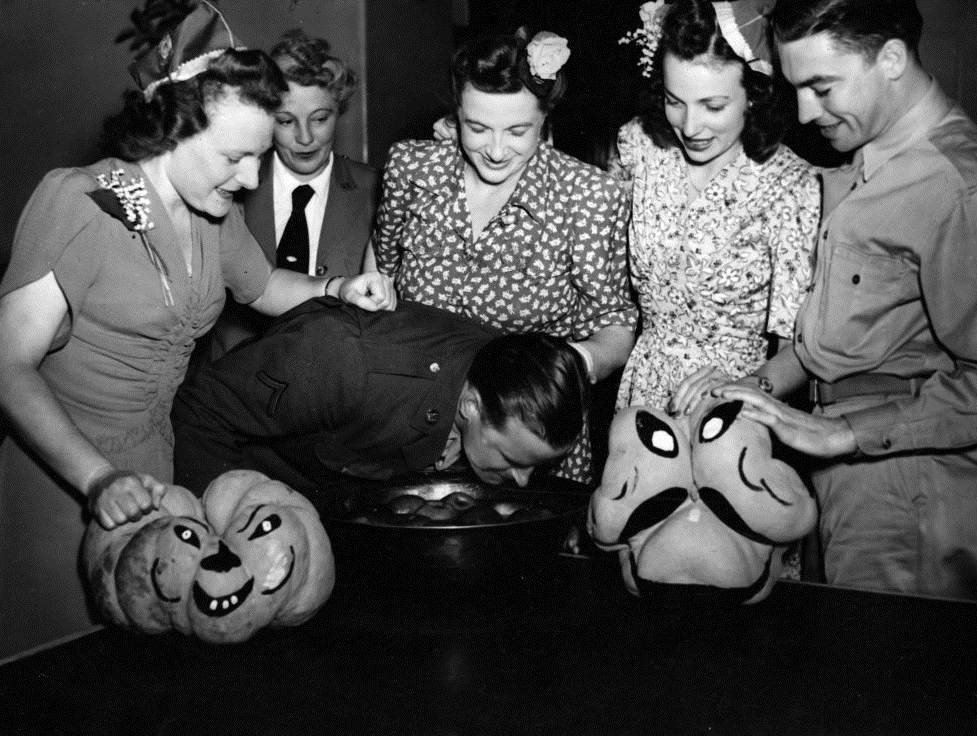 1940s vintage photo of a Halloween party for U.S. servicemen in 1943 featuring women in 1940s fashions and 1940s hairstyles. 