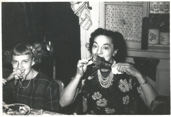 Late 1940s vintage photo of a woman and a young girl eating turkey legs during thanksgiving dinner. 