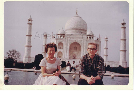 1960s vintage photo of a couple posing together in front of the Taj Mahal. 