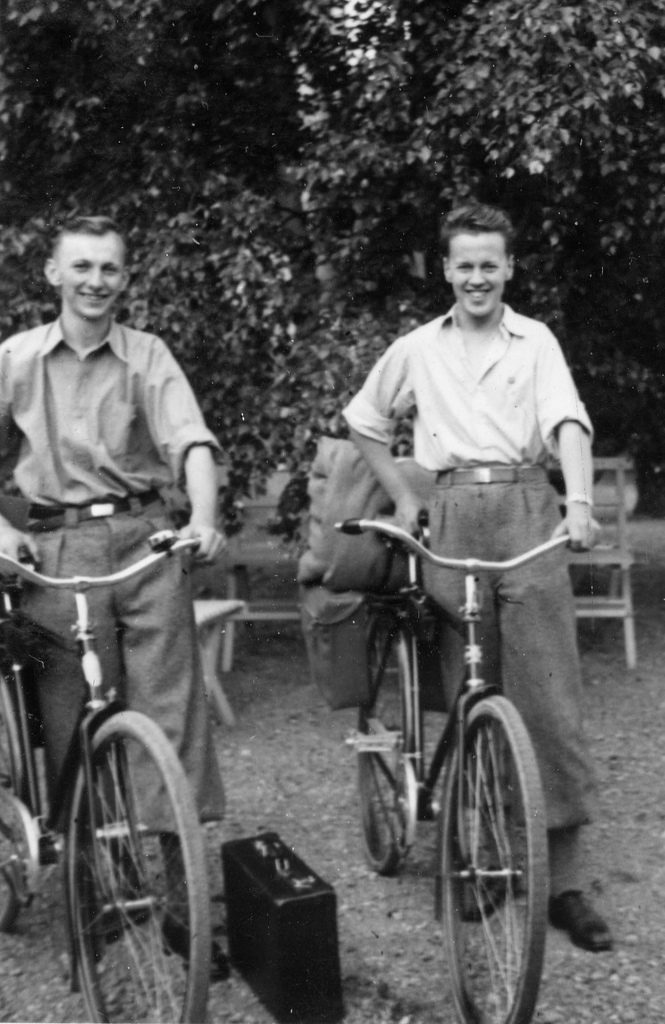 1930s vintage photo of 2 young men on bikes posing for a photo.