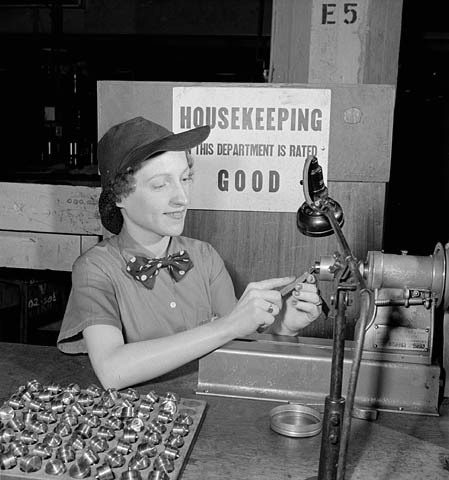 1940s vintage photo: ww2 canadian woman working for the war effort - Female munitions worker Françoise Corbeil turns out parts while listening to the piped music in her factory.