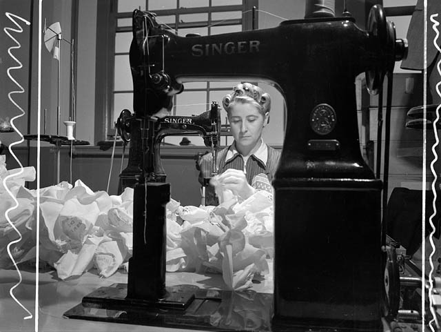 1940s vintage photo: ww2 canadian woman working for the war effort - a woman sewing cordite bags