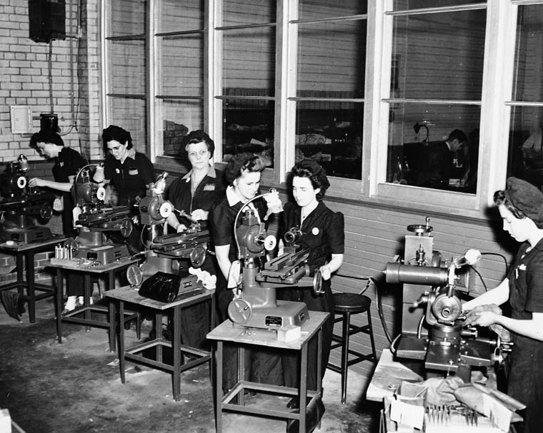 1940s vintage photo of women defense workers working at the factory in their factory uniforms. 