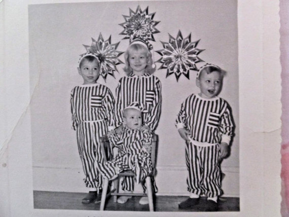 1950s  vintage photo of  kids in matching pajamas standing in front of Christmas decorations. 