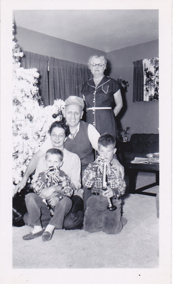 1950s family vintage photo of an older couple posing in front of their white christmas tree