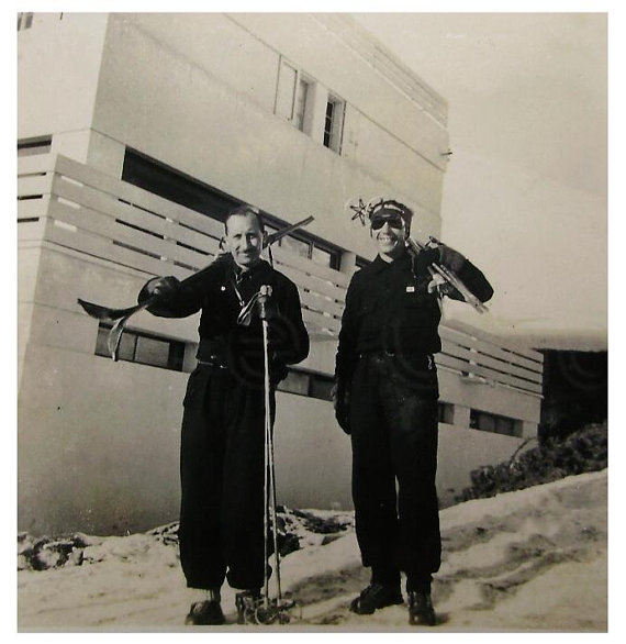 1930s vintage image of 2 men holding skiis and in ski outfits. 