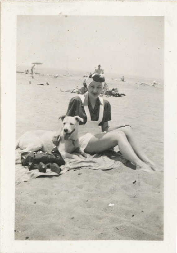 1940s vintage image of woman on the beach with dog in a playsuit and 1940s turban. 