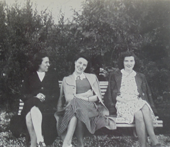 1940s vintage image of women sitting on a bench in 1940s fashions.