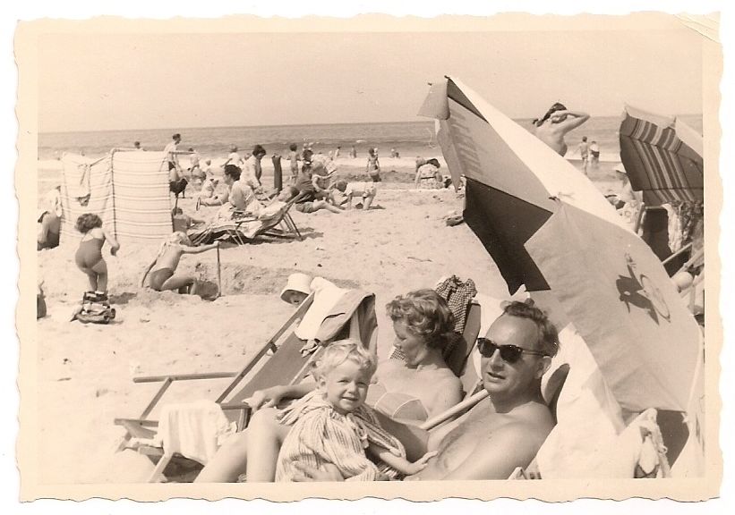 1950s vintage image of family on the beach in 1950s summer time fashions. 