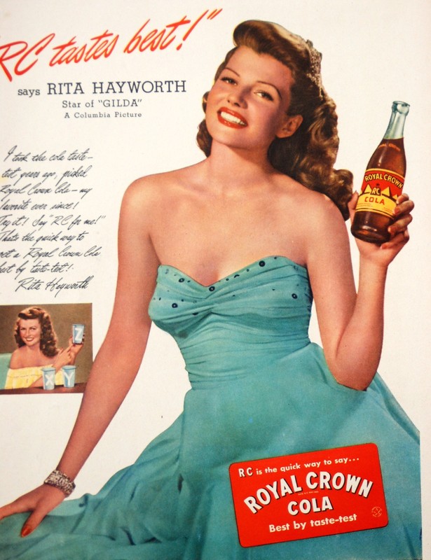 1940s vintage ad for Royal Crown Cola featuring Rita Hayworth in a 1940s evening gown holding a Royal Crown Cola.