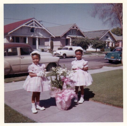 1960s vintage photo of two little Black girls in their easter dresses posing for a photo.