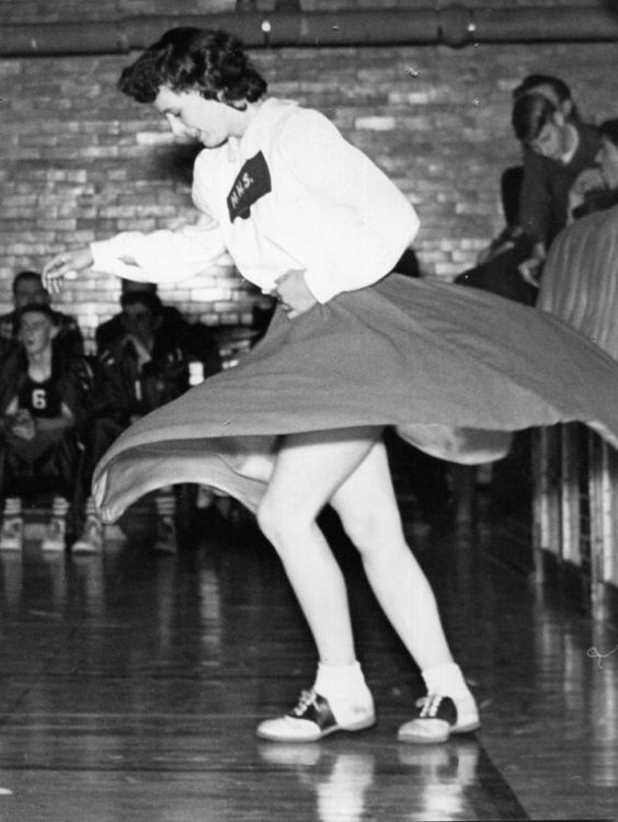 1950s Vintage Photo of a cheerleader wearing her cheerleading uniform and saddle shoes. 