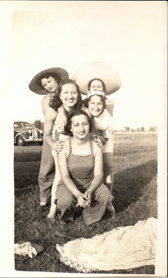 1940s vintage image of women at a picnic in 1940s fashions and fun summer hats. 