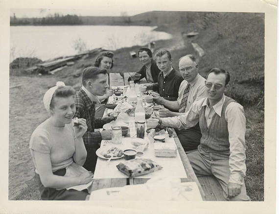 1940s vintage photo of a family enjoying a picnic by a lake. 